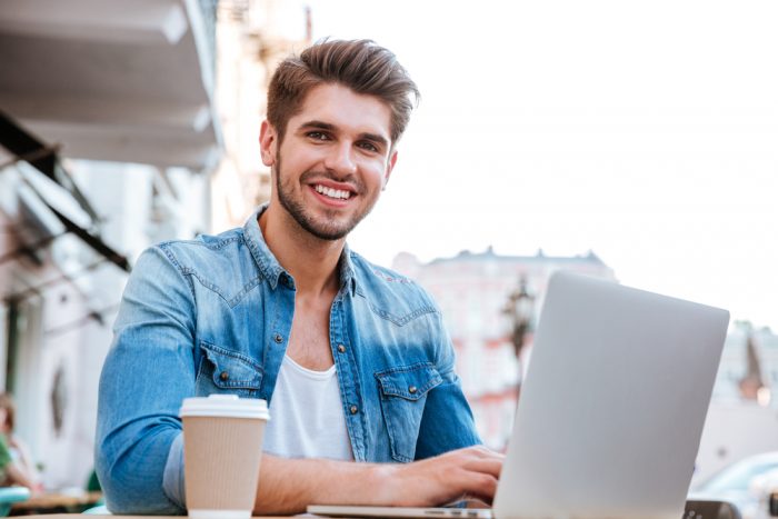Smiling,Cheerful,Casual,Man,Using,Laptop,While,Sitting,At,Cafe